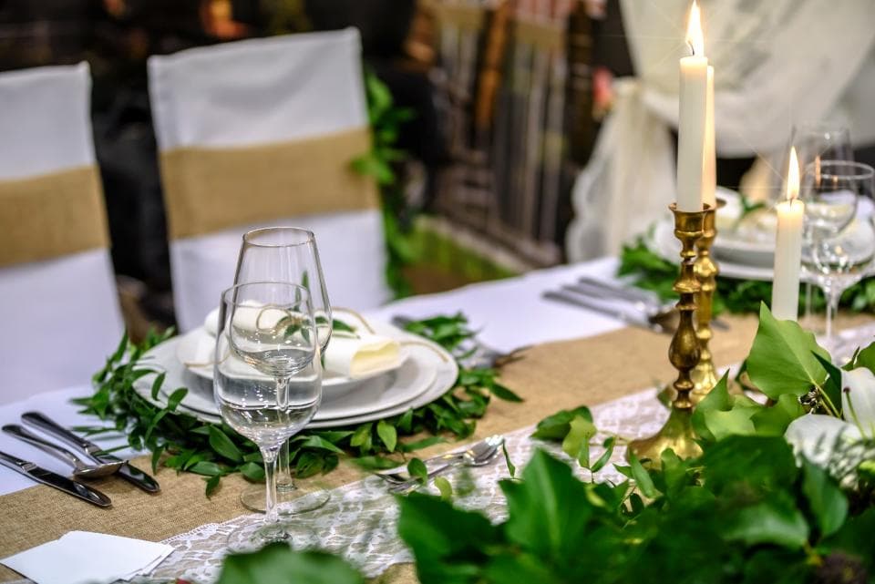 A long table set for a private dinner with candles and greenery