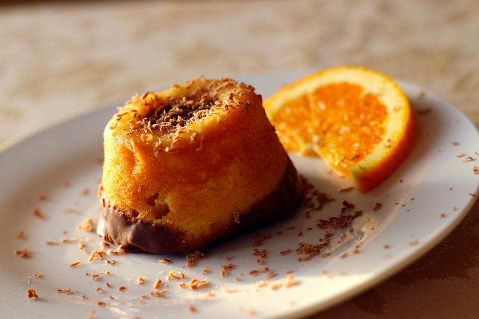 A small orange cake with a slice of fresh orange