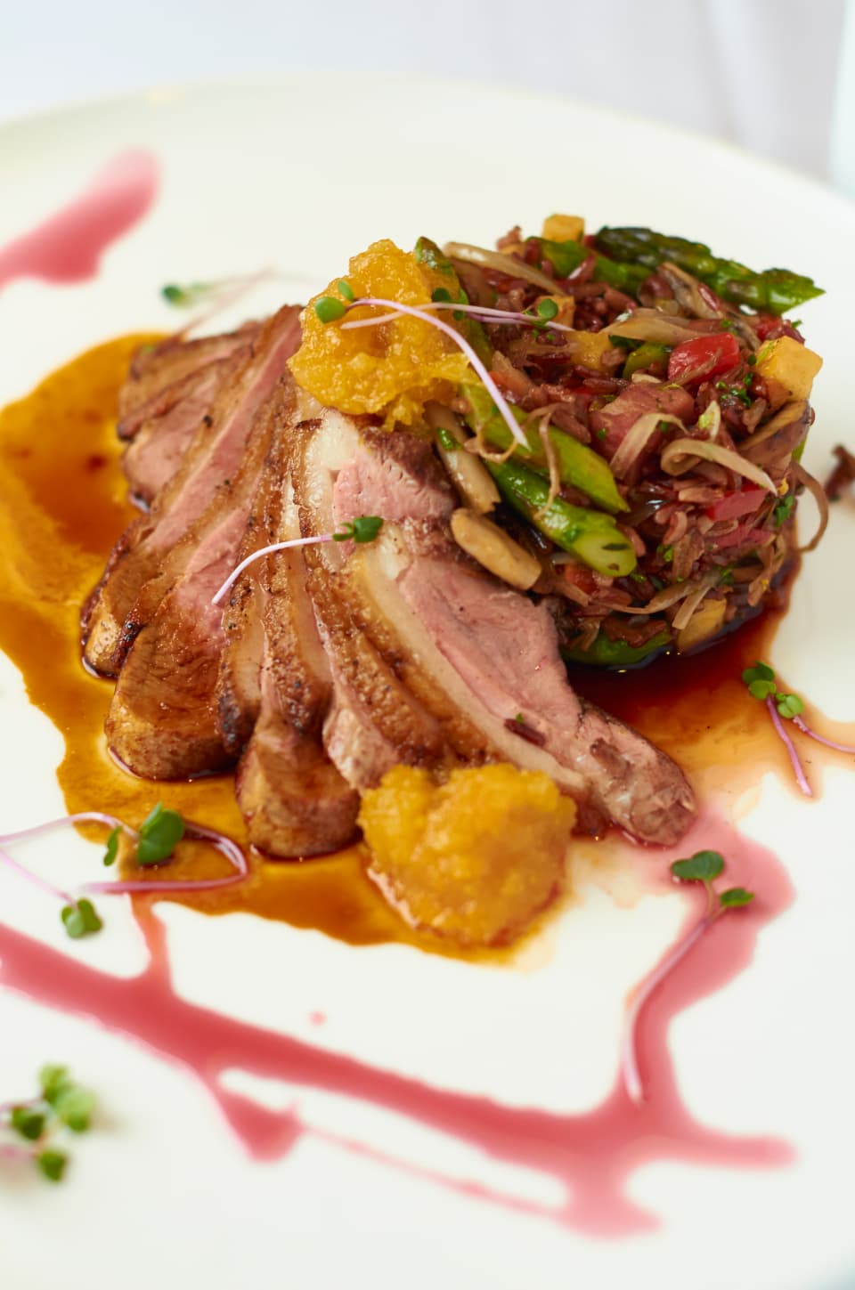 Sliced pork shoulder with sauce and herbs on a plate