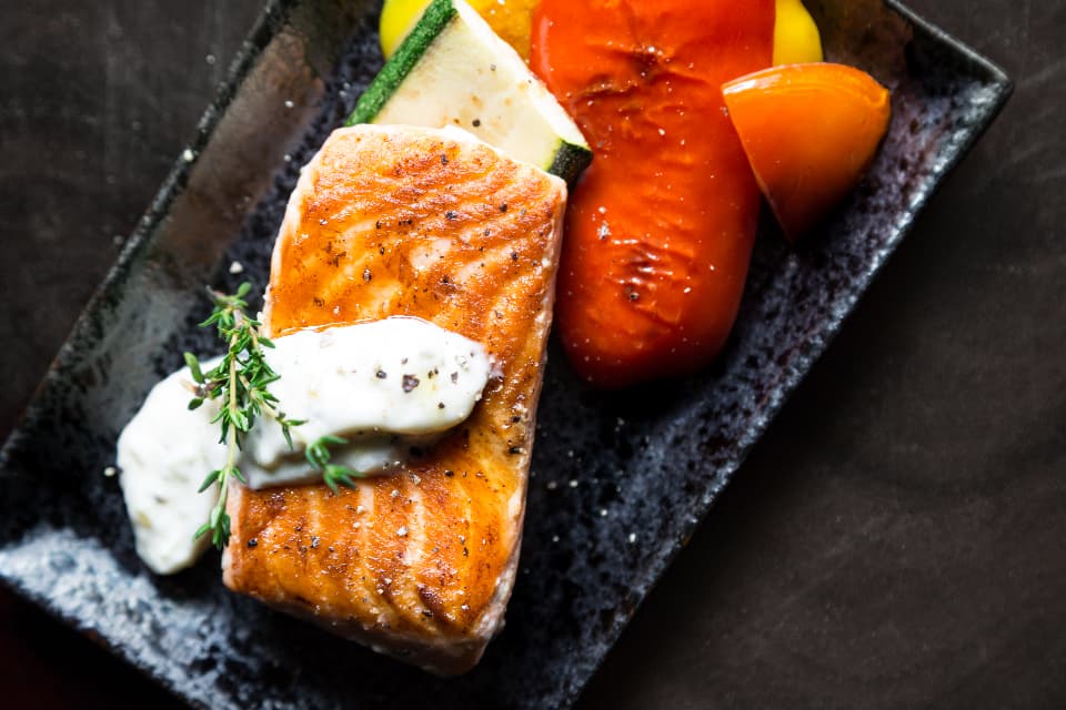 Grilled salmon fillet with charred peppers on a slate plate