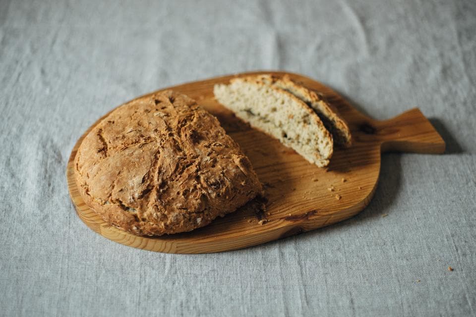 A loaf of house sourdough, sliced on a wooden board